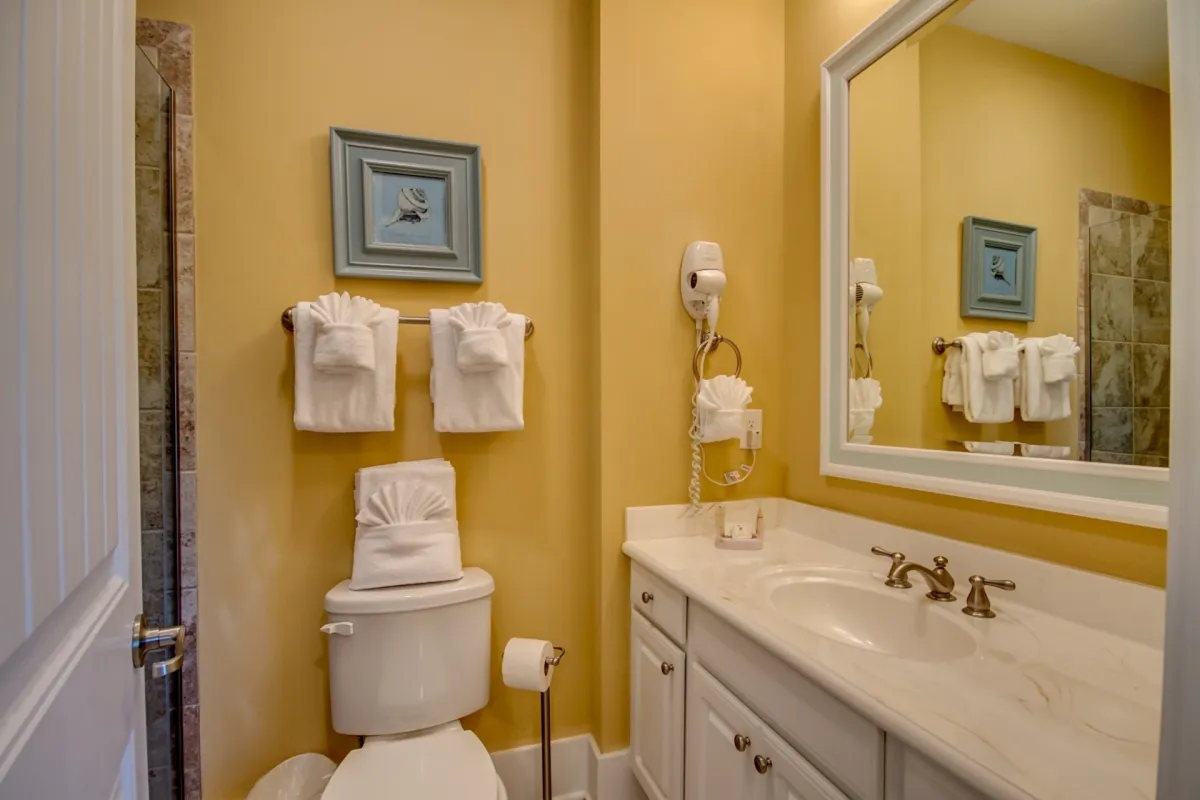A stylish ensuite bathroom is depicted, complete with a double-sink vanity, decorative artwork, and neatly arranged towels. The space feels spacious, serene, and well-appointed, ideal for personal grooming and unwinding after a day of adventure.